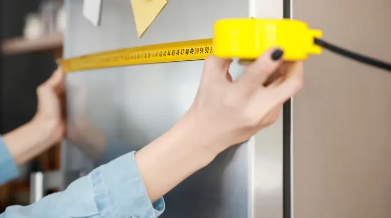 close-up-womans-hands-measuring-refrigerator